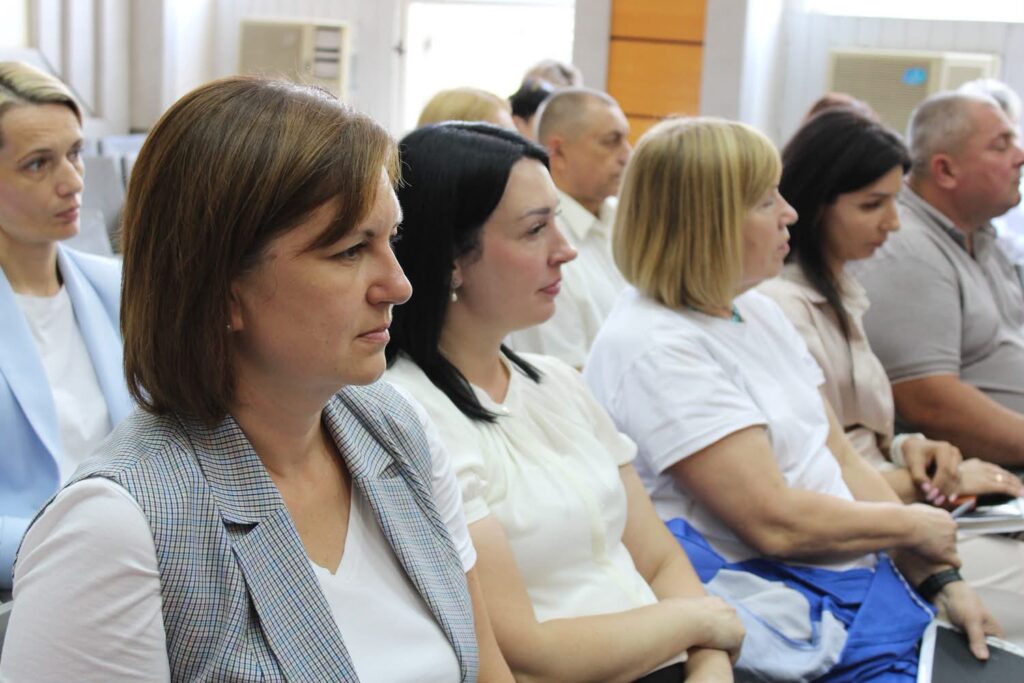 Група учасників сидить у конференц-залі під час засідання колегії Головного управління Пенсійного фонду України у Київській області та уважно слухає доповідача. На передньому плані — жінки в діловому одязі, позаду — інші присутні.